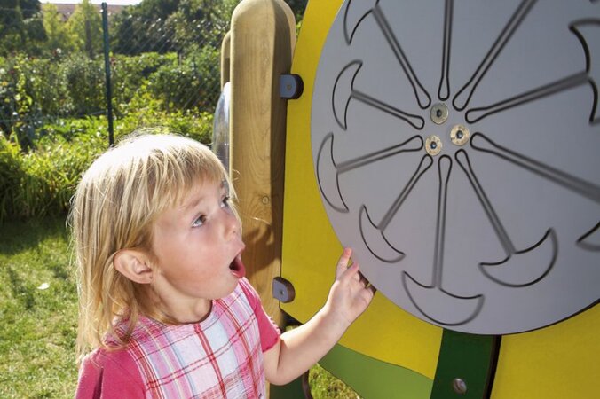 Playground equipment for childcare facilities from eibe - little girl turning a play wheel on a yellow eibe play board.