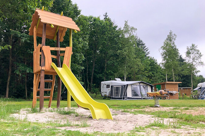 Playground equipment for camping facilities - three children swinging in nest swing.